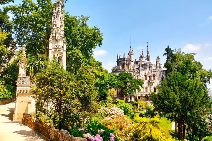 Lush gardens and intricate architecture of Quinta da Regaleira in Sintra, surrounded by vibrant greenery.