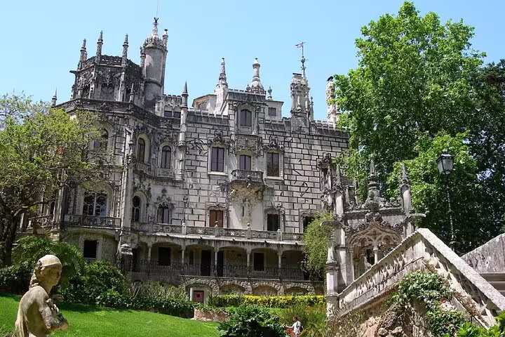 The ornate facade of Quinta da Regaleira in Sintra, displaying intricate Gothic architecture surrounded by lush greenery.