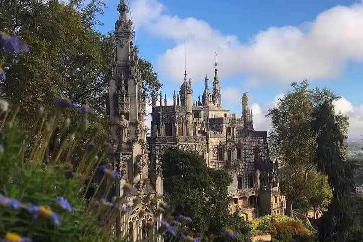 Discover the enchanting architecture of Sintra's Quinta da Regaleira, surrounded by lush greenery on a full-day tour with Pena Palace ticket.