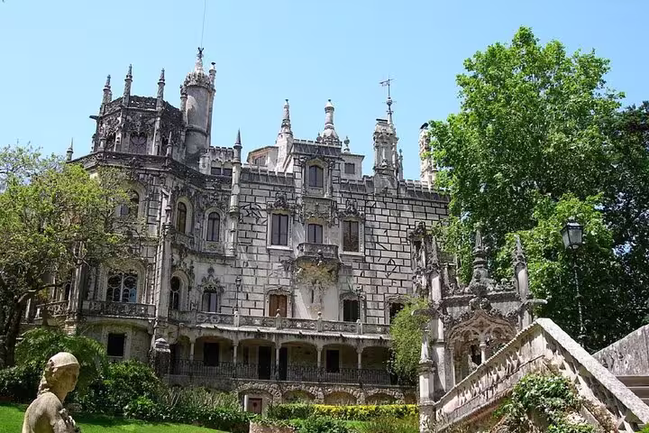 Majestic Gothic architecture of Sintra's Quinta da Regaleira surrounded by lush greenery, featured in a private full-day tour from Lisboa.