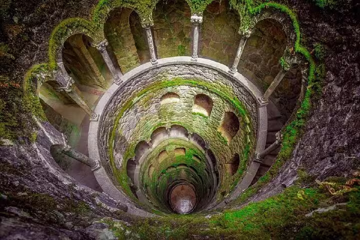 Enchanting spiral staircase of Quinta da Regaleira in Sintra, showcasing mystical architecture on the Sintra, Cabo da Roca & Cascais tour.