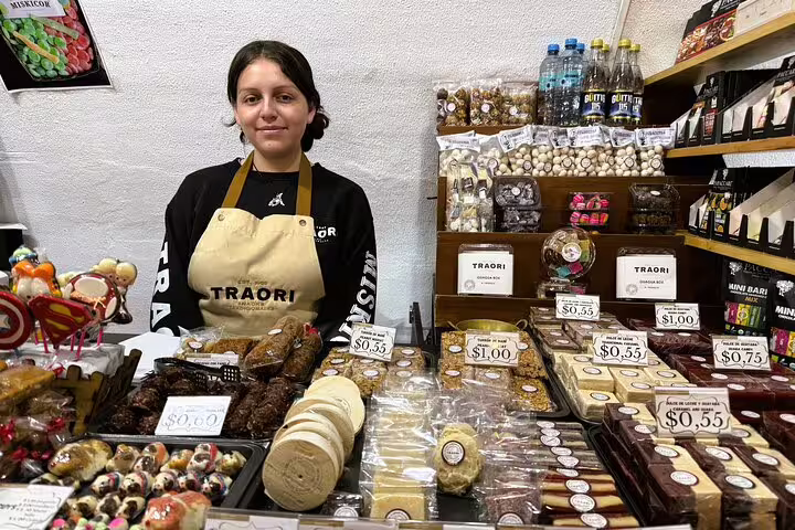 A friendly vendor presents an array of artisanal chocolates and local treats on the Quito Food and Cacao Tasting Tour in Hidden Gems.