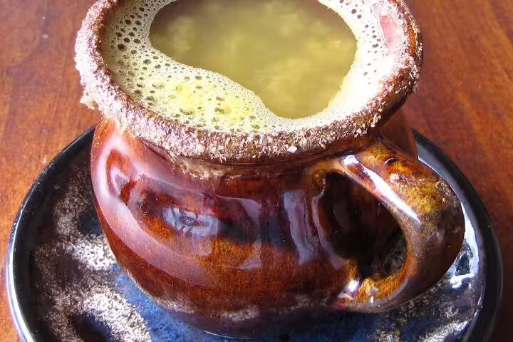 Rustic mug of traditional Ecuadorian drink on a saucer, featured in the Quito Food and Cacao Tasting Tour of hidden gems.