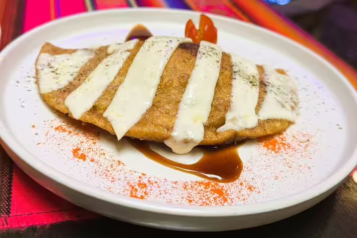 Delicious Ecuadorian dish with creamy sauce served on a vibrant plate, featured in Quito's hidden gems food and cacao tasting tour.