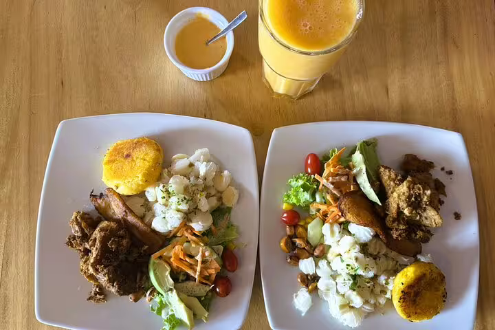 Plates of traditional Ecuadorian cuisine with fresh veggies, corn cakes, and juice, featured in Quito's hidden gems food tour.