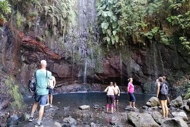 Hikers explore a lush waterfall setting during the Rabaçal 25 Fonts tour in Madeira's vibrant natural landscape.