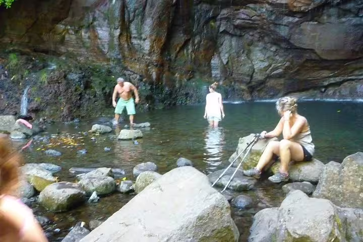Tourists relax and explore the serene pool and natural beauty at Rabaçal's 25 Fontes, a top attraction in Madeira.