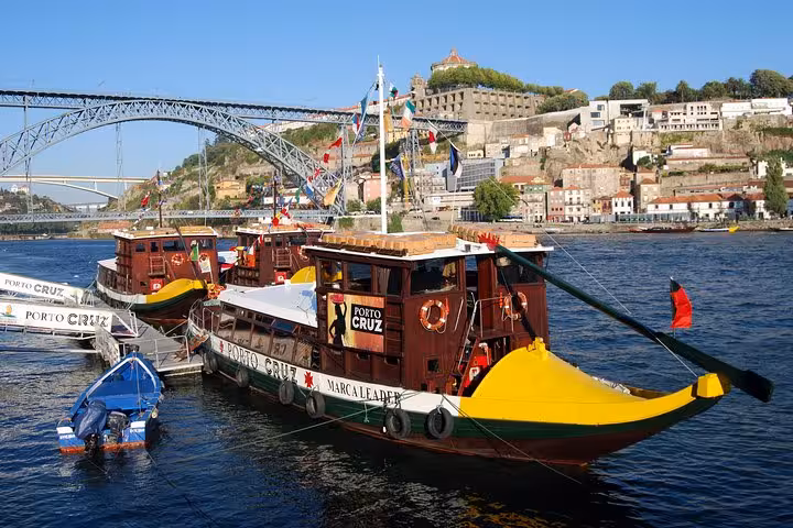 Scenic view of traditional Rabelo boats on the Douro River in Porto, with iconic bridges and cityscape in the background.