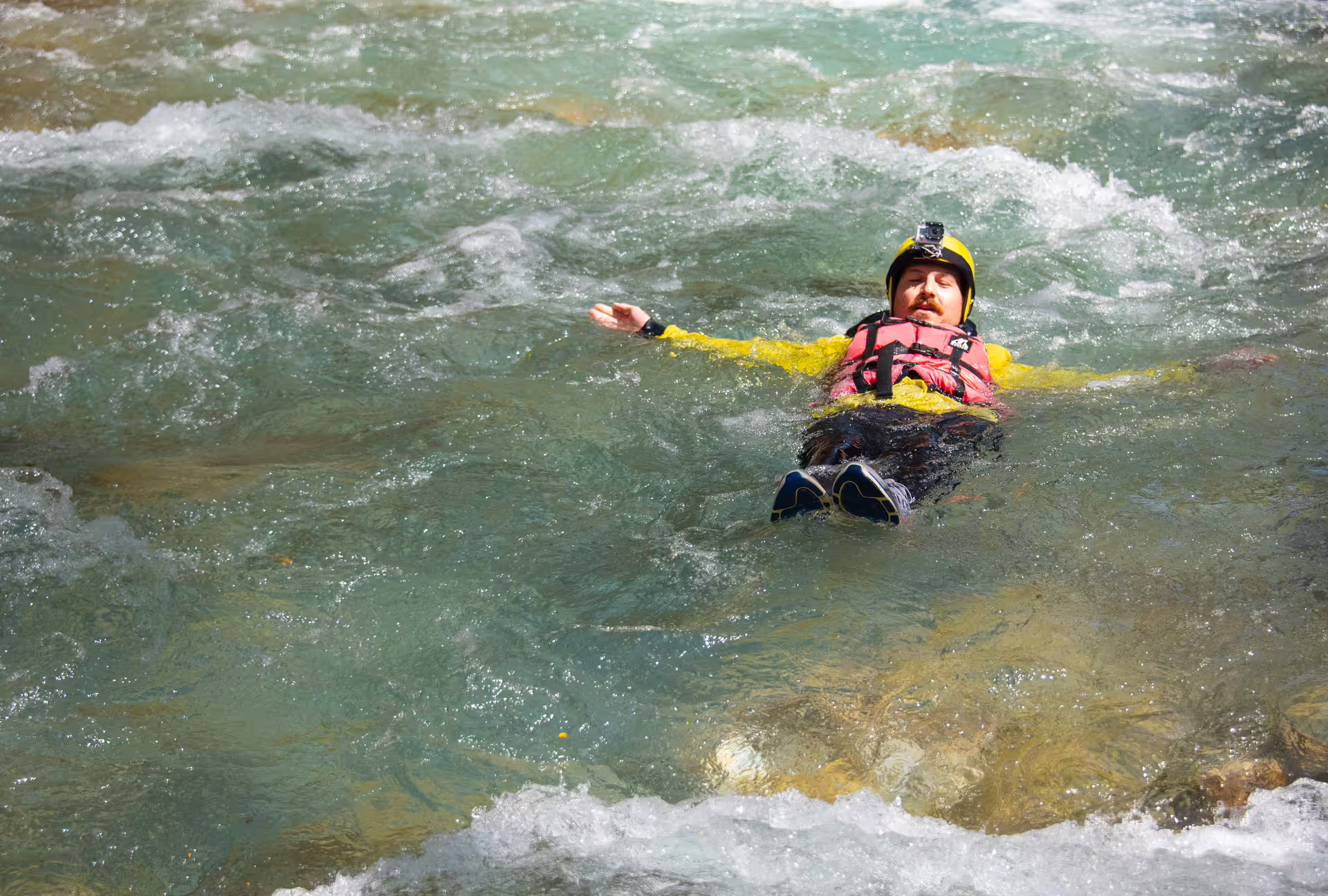 Rafter floating in clear river wearing helmet and life jacket on Lousios and Alfeios rafting tour in Greece