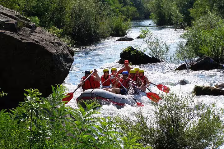 Group rafting the Cetina River past boulders and greenery, adventure day trip with Makarska transfer