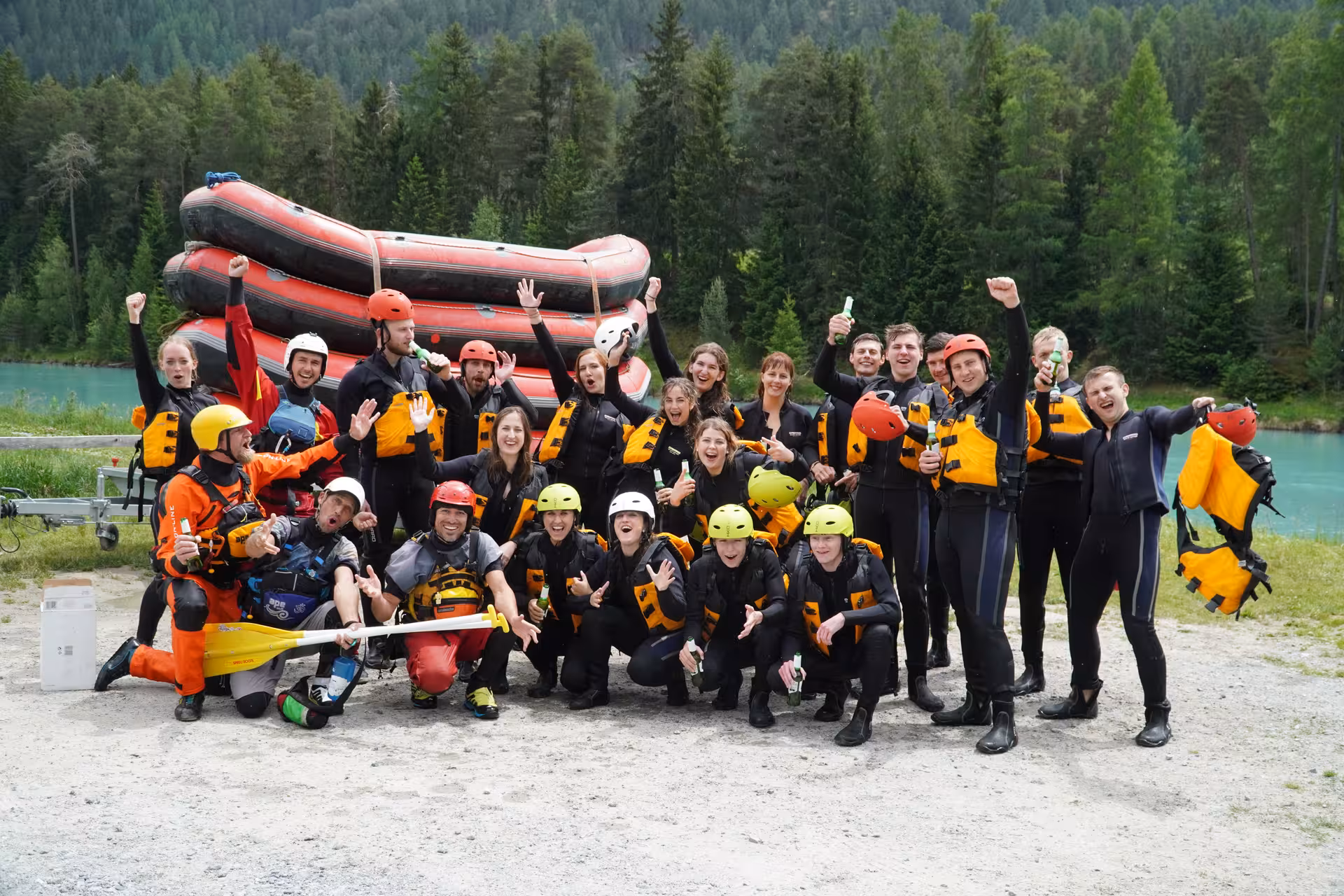 Group of rafters celebrating their whitewater adventure by the river in Interlaken, surrounded by scenic Swiss nature.