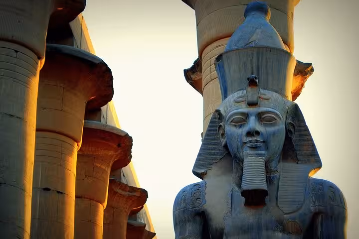 Colossal Ramses II statue at Luxor Temple during Hurghada excursion, iconic pharaoh monument at sunset