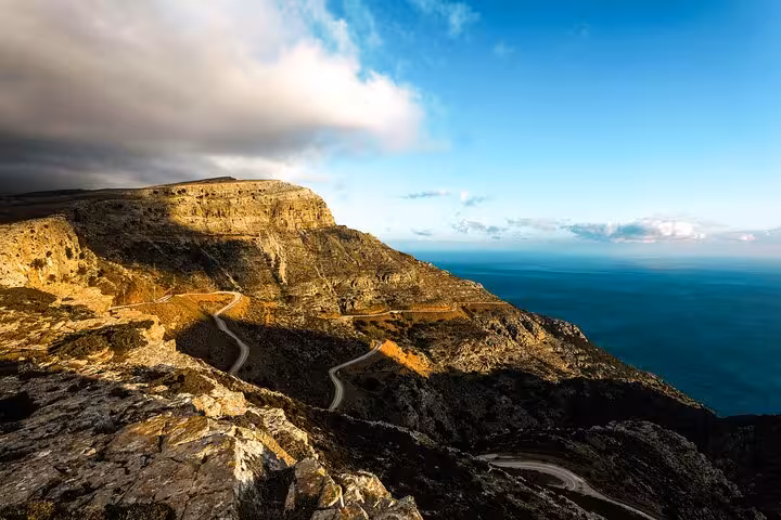 Dramatic coastal mountain landscape on Ikaria with winding road leading to the Aegean Sea on the Randi’s Forest hiking route