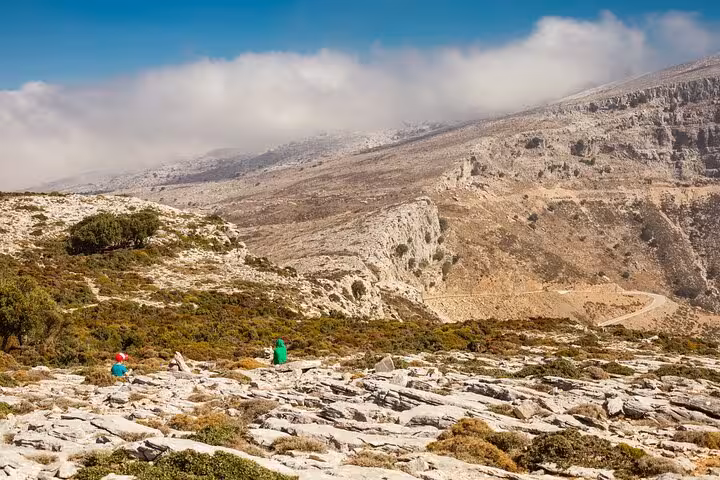 Wide view of hikers crossing rugged Ikaria mountains near Randi’s Forest on guided trail to Seychelles Beach and lunch stop