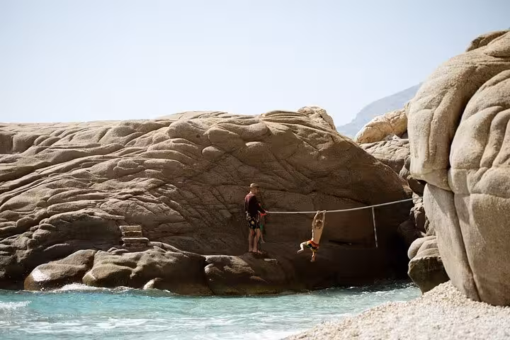 Family adventure on Ikaria’s sculpted Seychelles rocks, kids swinging over turquoise Aegean Sea on Randi Forest hike tour
