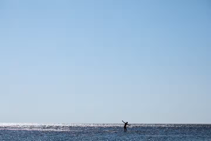 Traveler paddleboarding across the calm Aegean Sea near Ikaria’s Seychelles Beach on Randi Forest hiking and boat tour