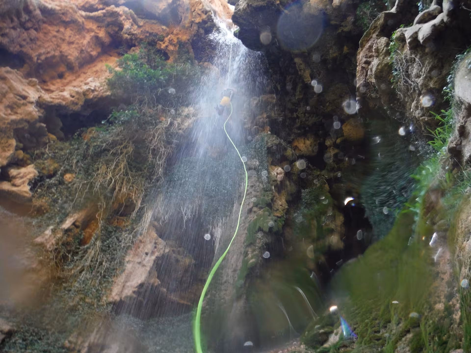 Rápel bajo una cascada en el barranco acuático de Riodeva, Teruel, barranquismo con agua y roca caliza