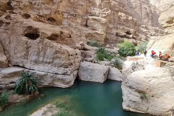Scenic canyon with turquoise water and hikers, a highlight of Ras Al Hadd two-day private tours.