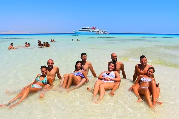 Guests relax on White Island sandbar with VIP boat in background on Ras Mohamed snorkeling tour