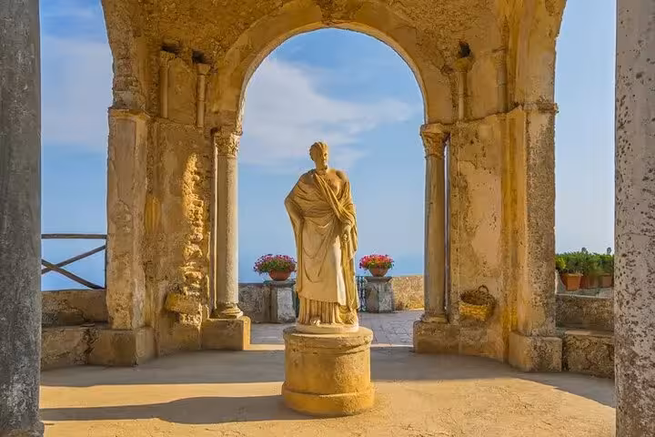 Ancient statue framed by an archway in Ravello with sea views, part of a cultural half-day tour.