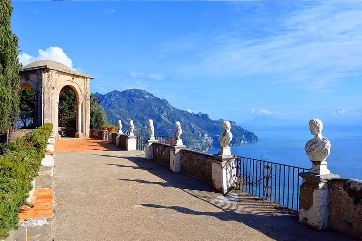 Scenic view of Ravello's coastal terrace with statues overlooking the Mediterranean on a sunny day.