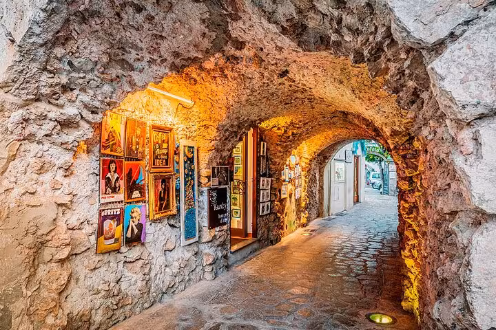 Wander through Ravello's charming stone archway, lined with vibrant artwork and illuminated by warm, inviting lights.