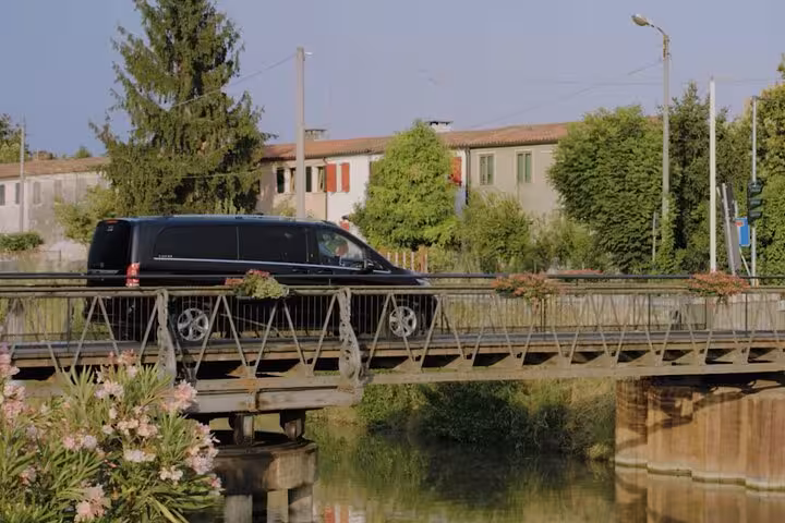 Black van crossing a picturesque bridge, showcasing transfer journey from Ravenna Cruise Terminal to Venice with scenic views.