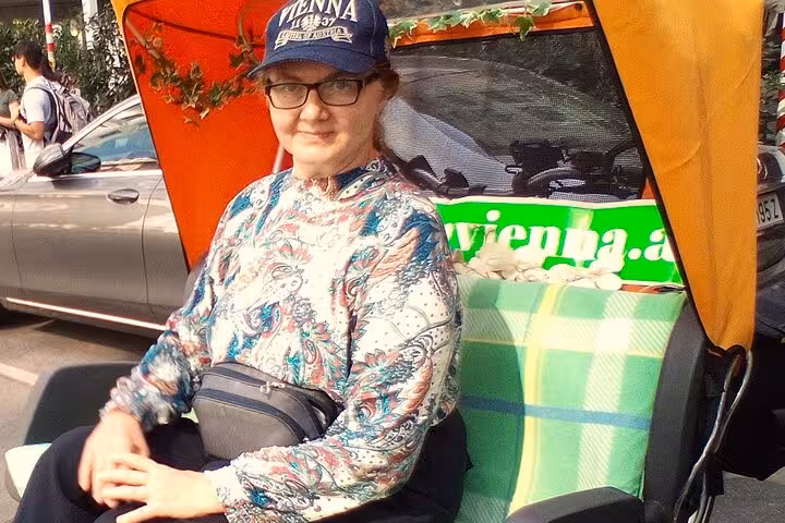 Traveler seated in RAXI e-rickshaw with orange canopy, enjoying a big private Vienna tour experience