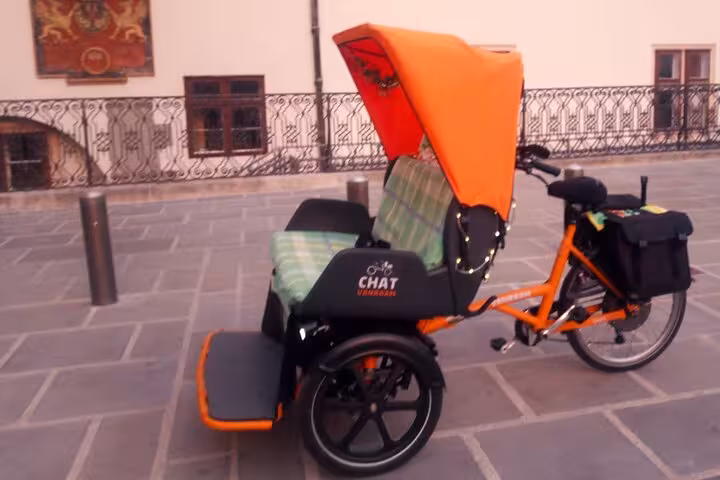 Orange canopy RAXI e-rickshaw parked in Vienna old town, ideal for a big private sightseeing tour