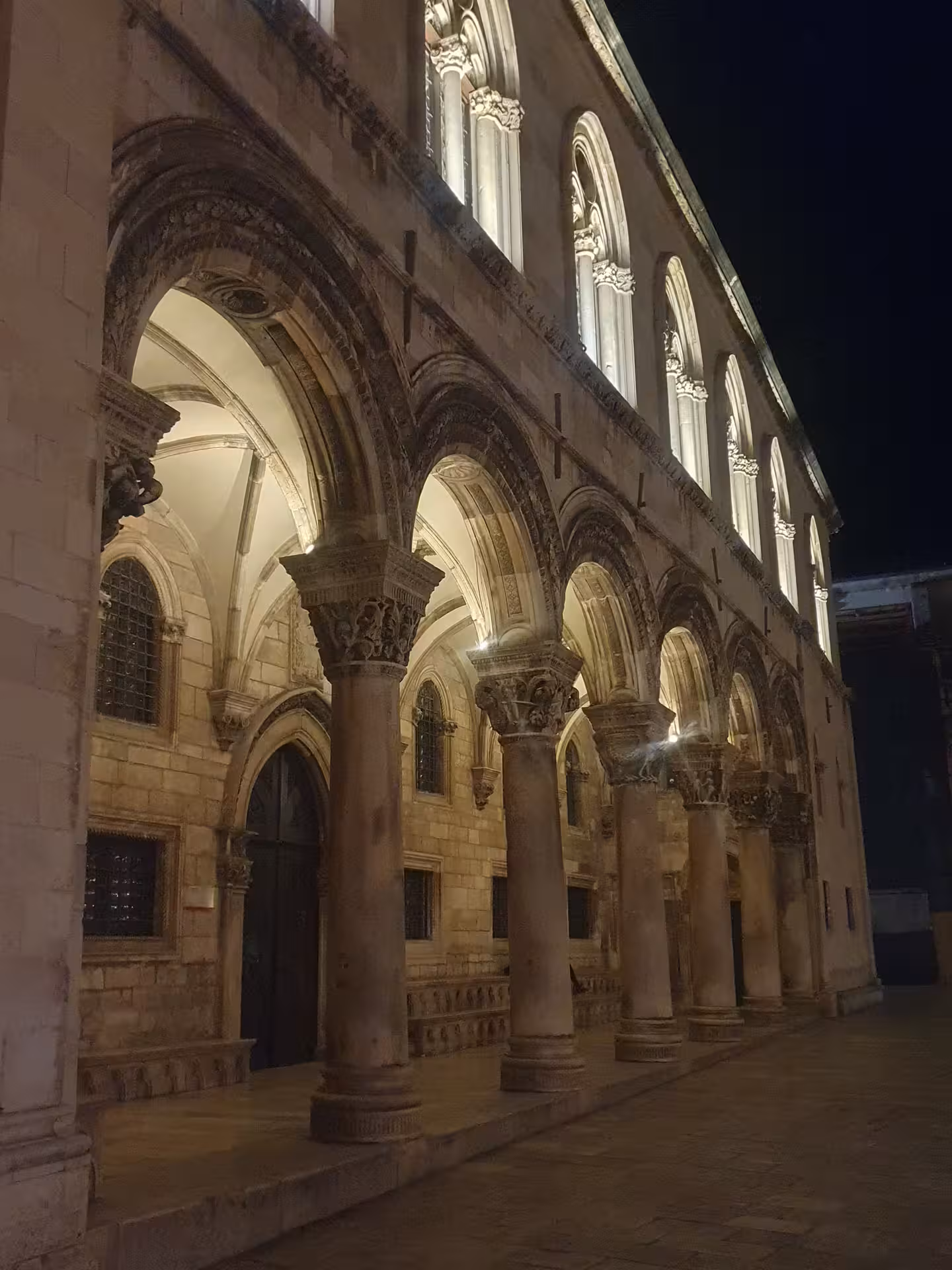 Illuminated Rector’s Palace arches in Dubrovnik Old Town at night, highlight of the history by night tour