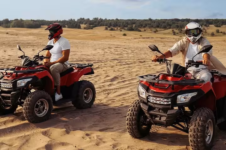 Two riders on red ATVs driving across sandy dunes in Sharm El Sheikh Sinai desert adventure excursion