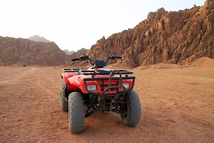 Red ATV quad bike parked on sandy Sinai desert valley near Sharm El Sheikh, ready for safari adventure tour