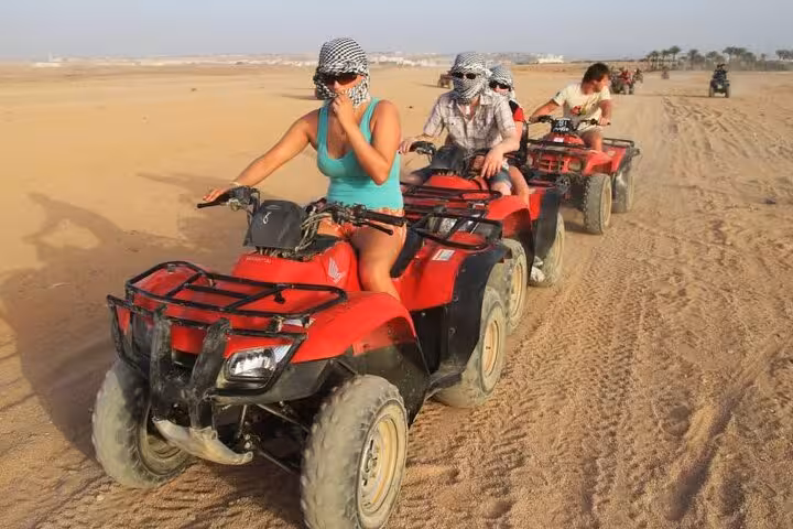 Group riding red ATVs across Hurghada desert on quad bike safari tour with helmets and scarves