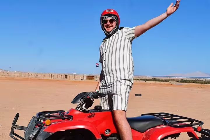 Rider on red ATV quad bike in Sinai desert, Sharm El Sheikh safari adventure tour with helmet and blue sky