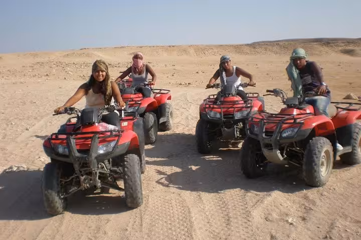 Riders on red ATVs during Sharm El Sheikh quad bike safari, guided desert adventure across sandy tracks
