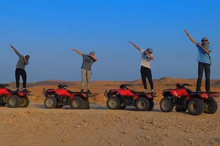 Friends posing on red ATVs in Hurghada desert during 3-hour quad safari adventure tour at sunset