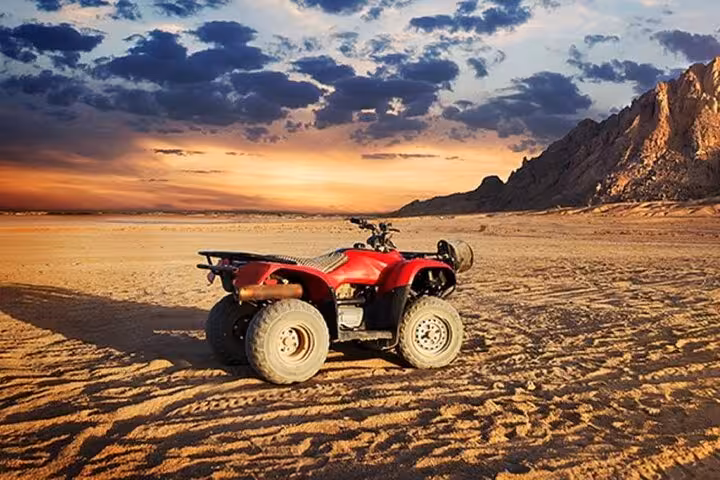 Red ATV quad bike in Sharm El Sheikh desert at sunset with Echo Mountain backdrop, thrilling safari tour
