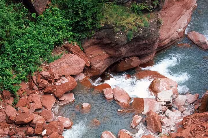 Scenic view of rushing water flowing through unique red rock formations in Red Canyon, ideal for nature tours.