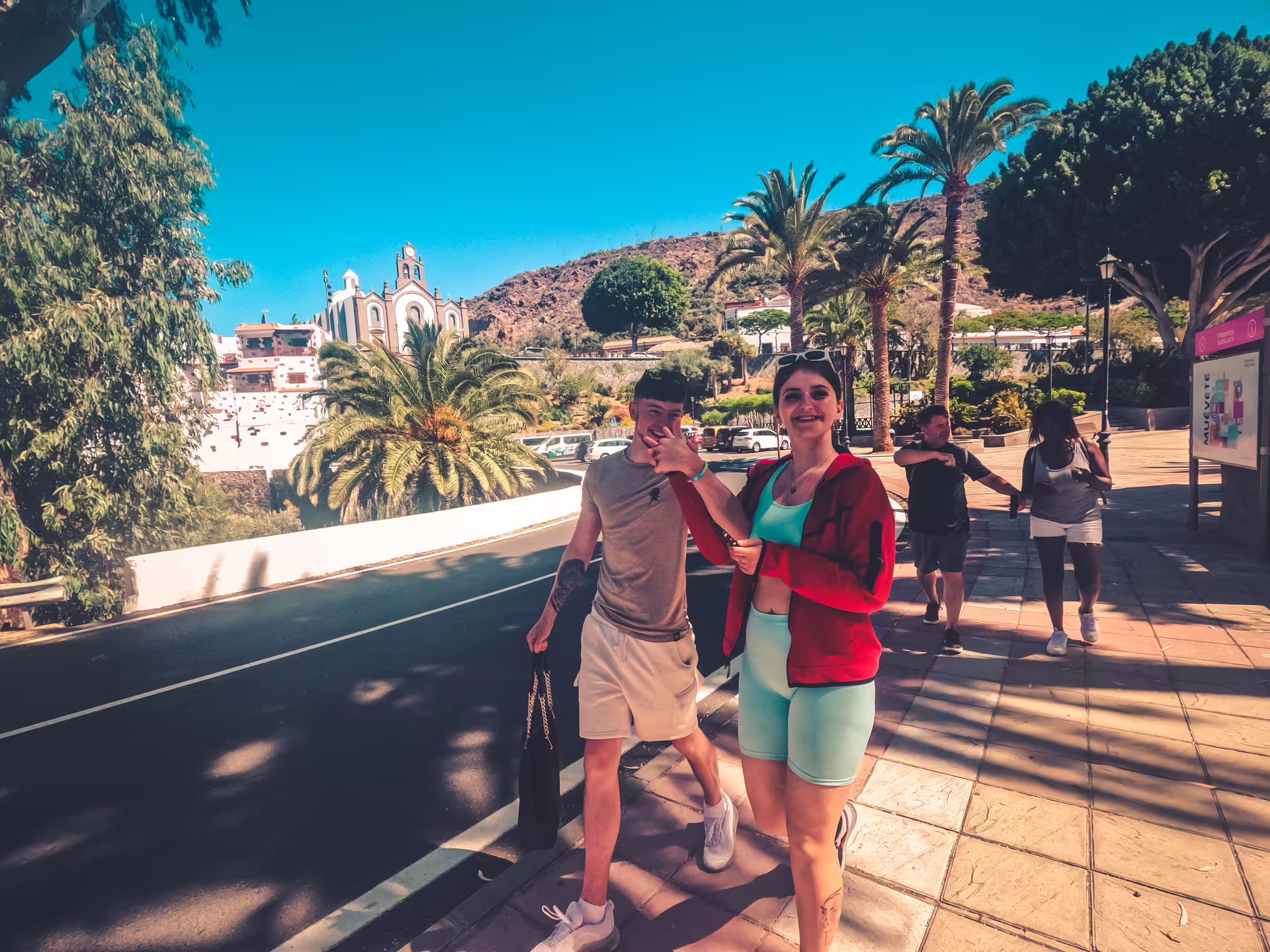 Tour participants walking along a scenic pathway lined with palm trees and historic architecture on the Red Canyon Tour.