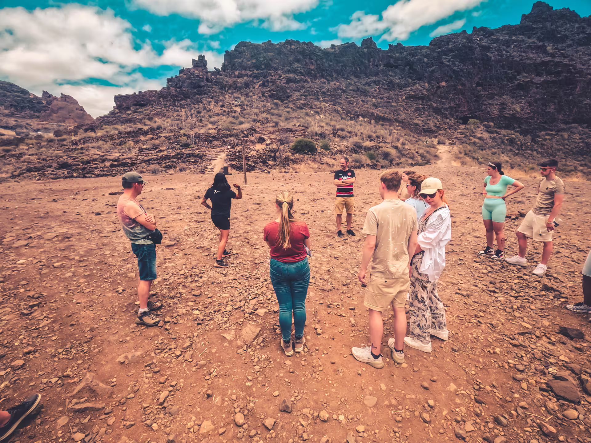 A small group explores the rugged terrain of the Red Canyon on a guided tour under a vibrant blue sky.