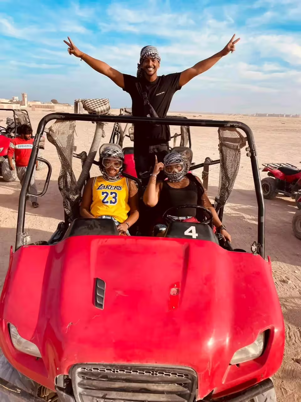 Red dune buggy photo stop on Mega Safari Hurghada desert tour with goggles and Bedouin scarves under blue sky