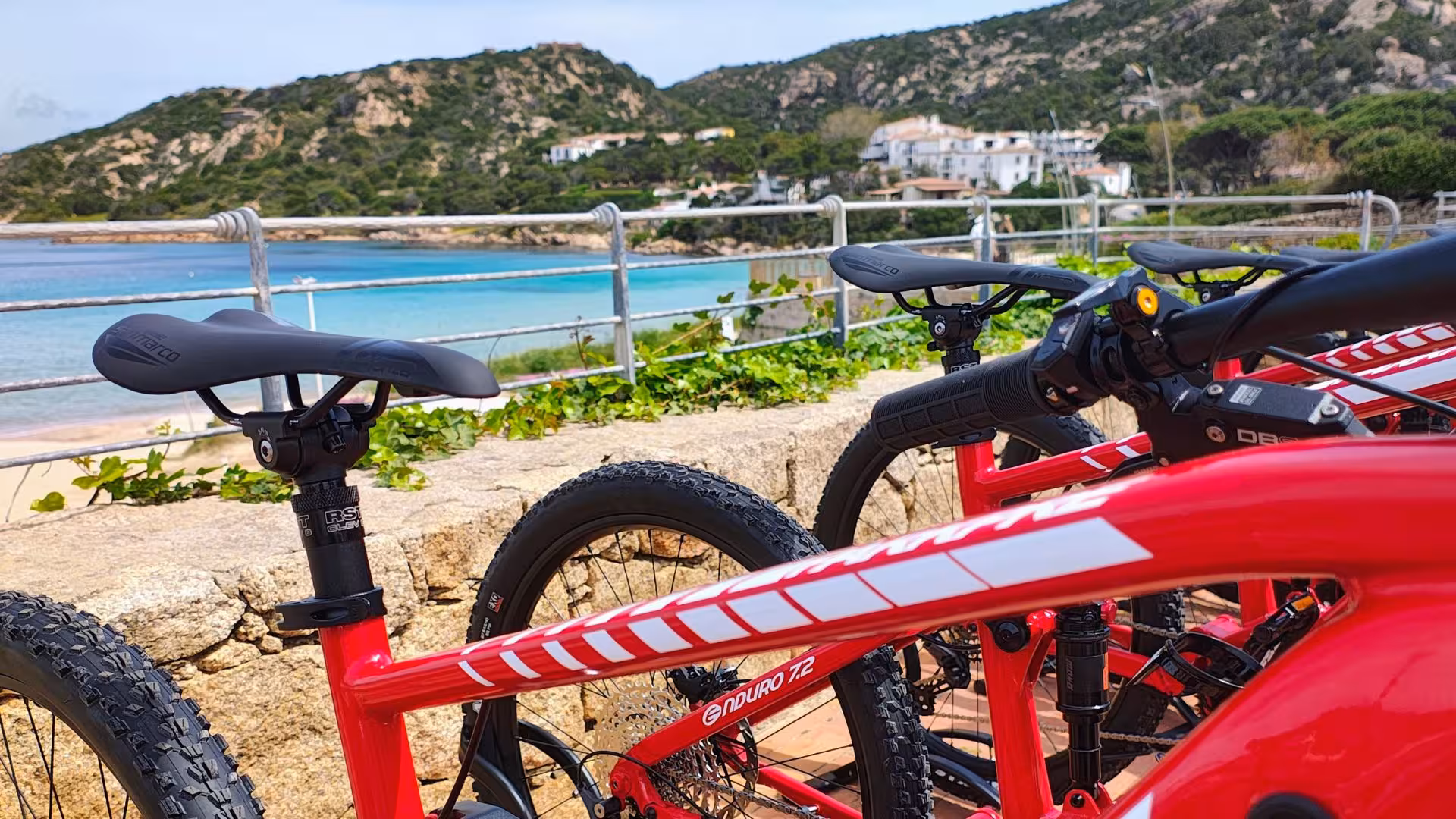 Close-up of red e-bikes with coastal backdrop in Palau, perfect for exploring Caprera or La Maddalena on a guided tour.