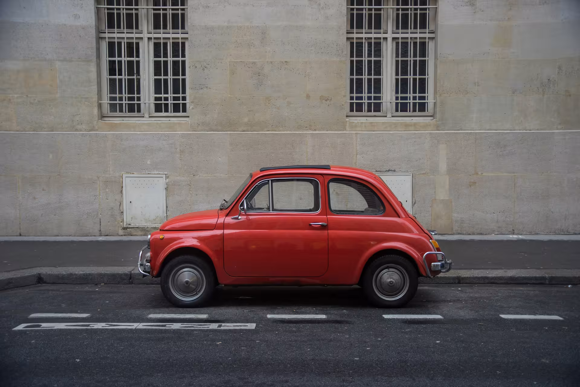 Classic red Fiat '500 parked on a city street, perfect for the Ancient Ostia vintage tour.