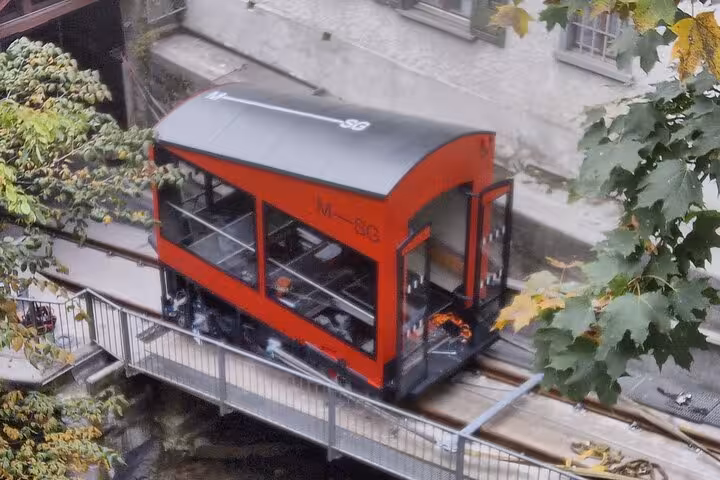 Red funicular railway in St. Gallen, surrounded by leafy trees, part of the scenic St. Gallen & Appenzell tour.
