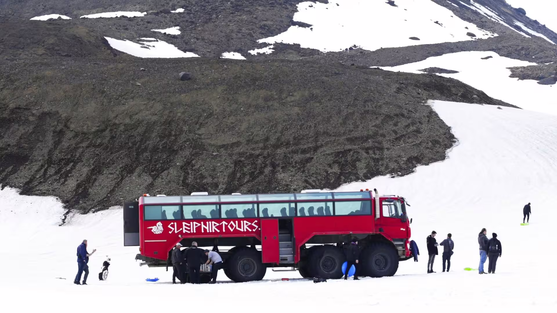 Red glacier monster truck parked on Langjökull snowfield with guests, unique Gullfoss to glacier tour Iceland