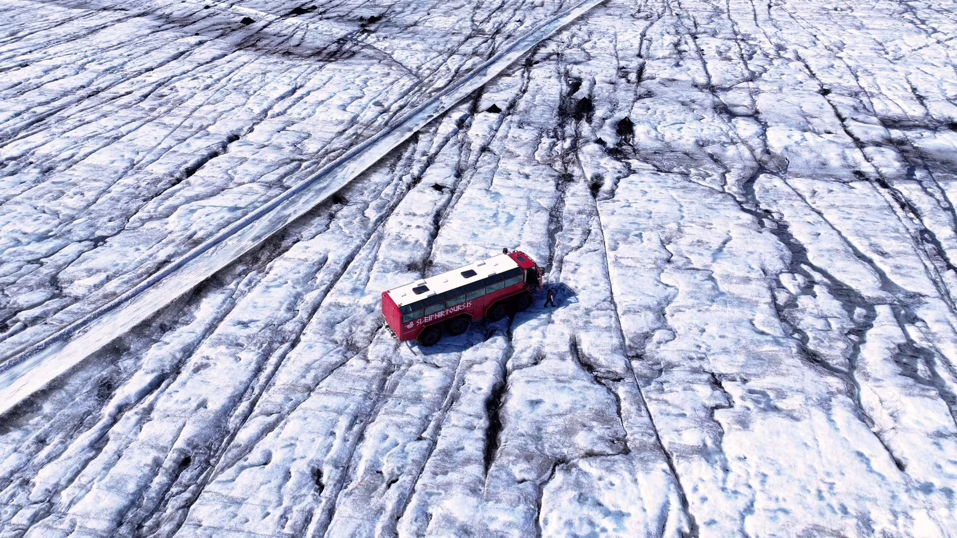 Red Glacier monster truck on Langjökull ice field near Gullfoss, Iceland, with dramatic crevasse patterns