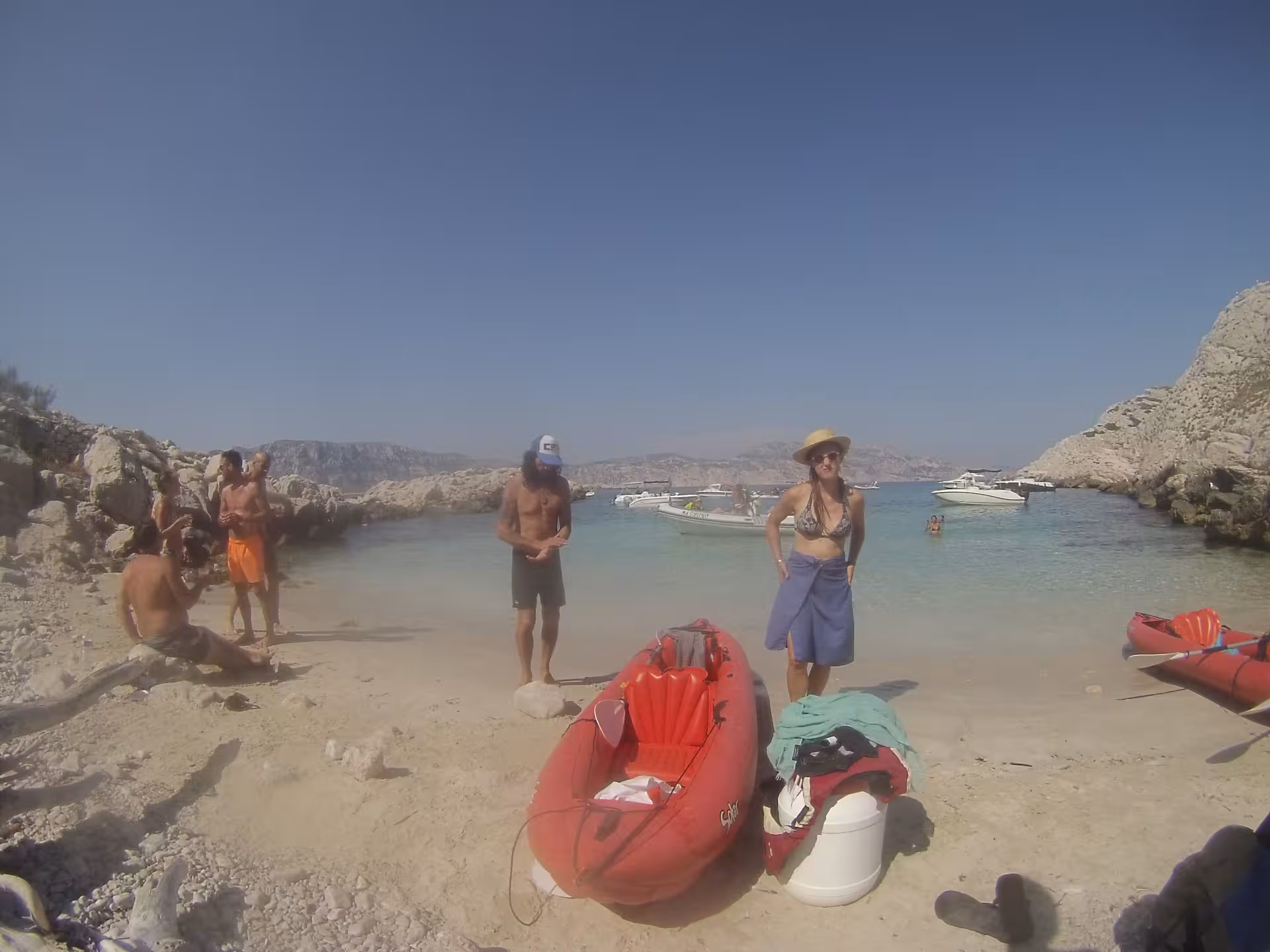 Red kayak on a sandy cove in the Calanques near Marseille, turquoise water and boats on a sunny day