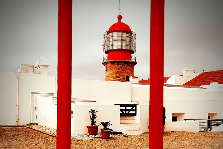 Historic red lighthouse view framed by vibrant architecture on Algarve Natural Park West Coast tour.