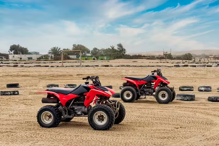 Two red quad bikes parked on a sandy terrain, ready for an exciting self-drive desert tour.