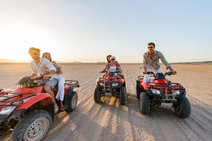 Friends driving red quad bikes across sandy desert on a private ATV quad safari adventure from Sharm El Sheikh
